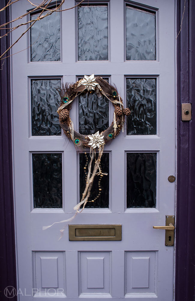 Peacock feathers Christmas wreath on purple door